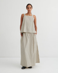A model stands against a plain white studio background wearing a sleeveless beige and white vertically striped two-piece set consisting of a cropped top and matching wide-leg skirt.