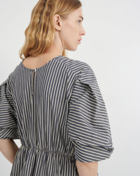 A woman shown from the back wearing a dark gray and white vertically striped dress with puff sleeves and a gathered waist, photographed against a clean white studio background.
