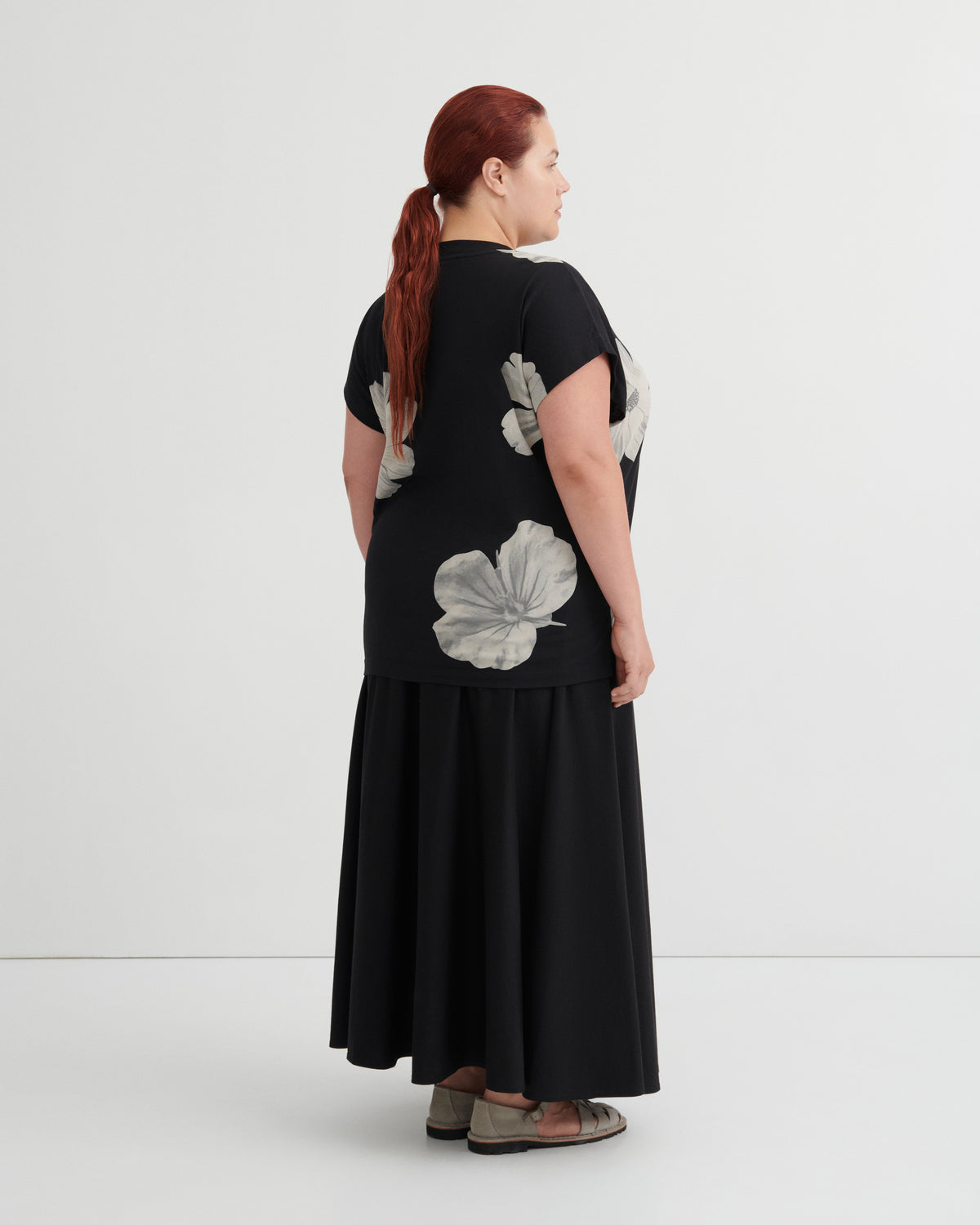 Woman wearing a black dress with floral patterns on a white background