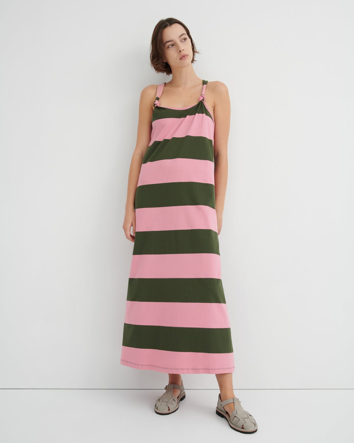 Woman wearing a pink and green striped dress against a white background