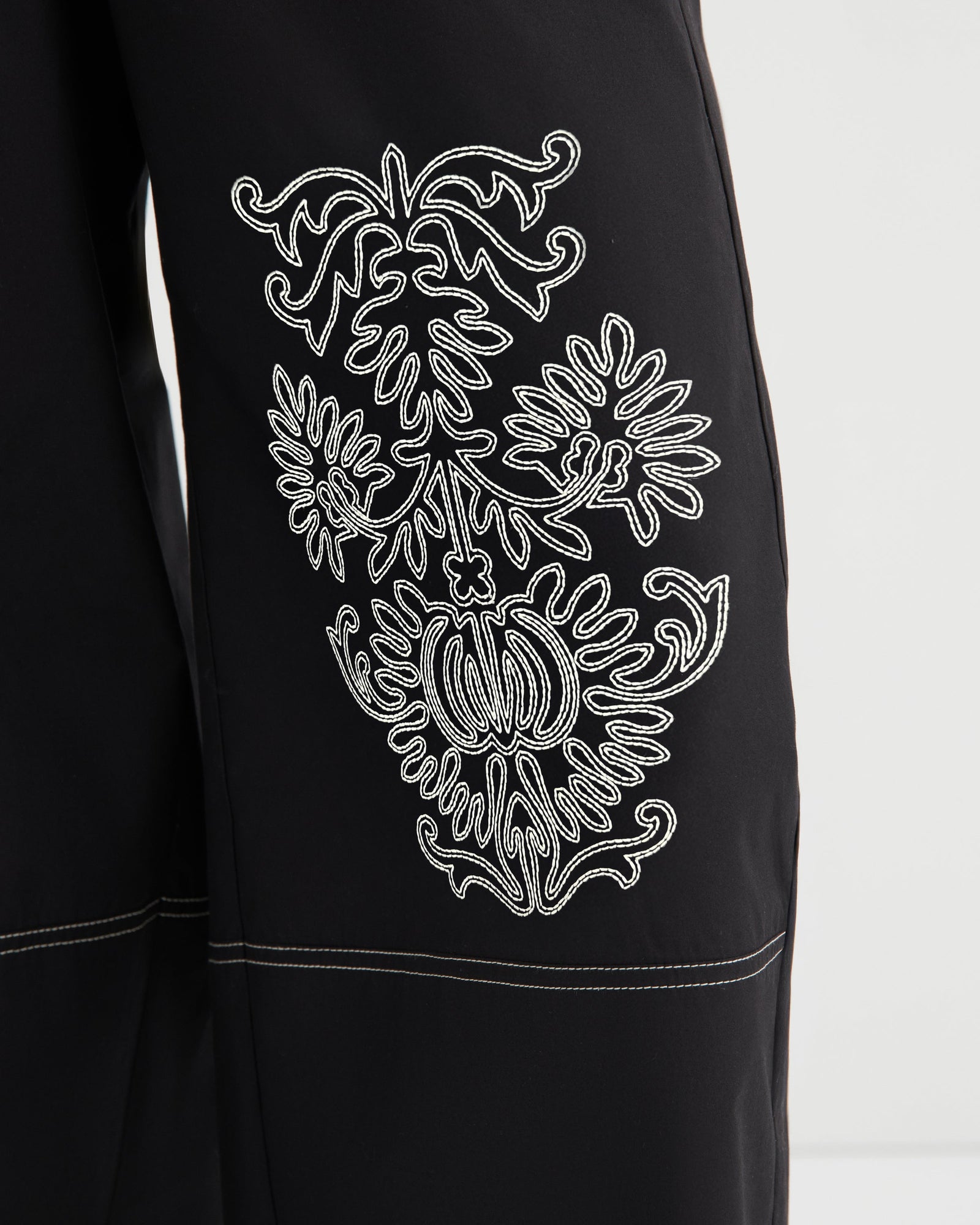Black garment with white embroidered design on a white background
