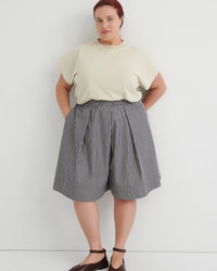 Person wearing a light-colored top and striped skirt against a white background