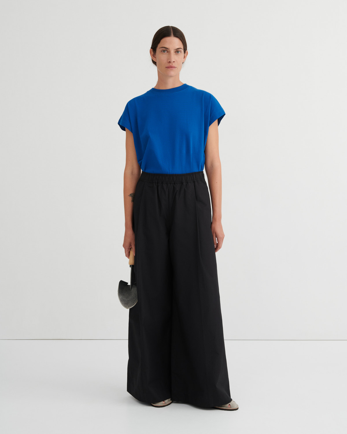 Woman wearing a blue top and black pants on a white background