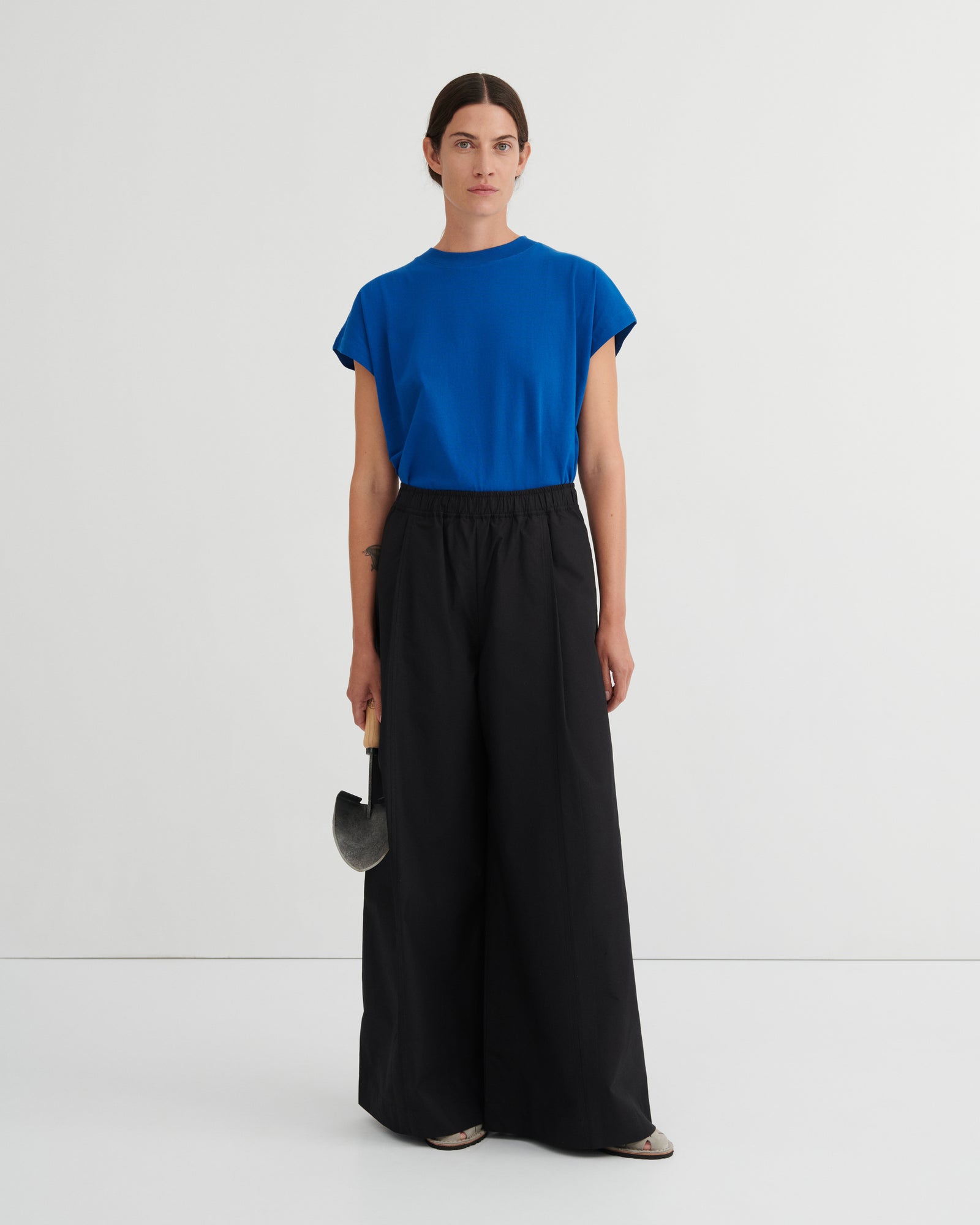 Woman wearing a blue top and black pants on a white background