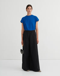 Woman wearing a blue top and black pants on a white background