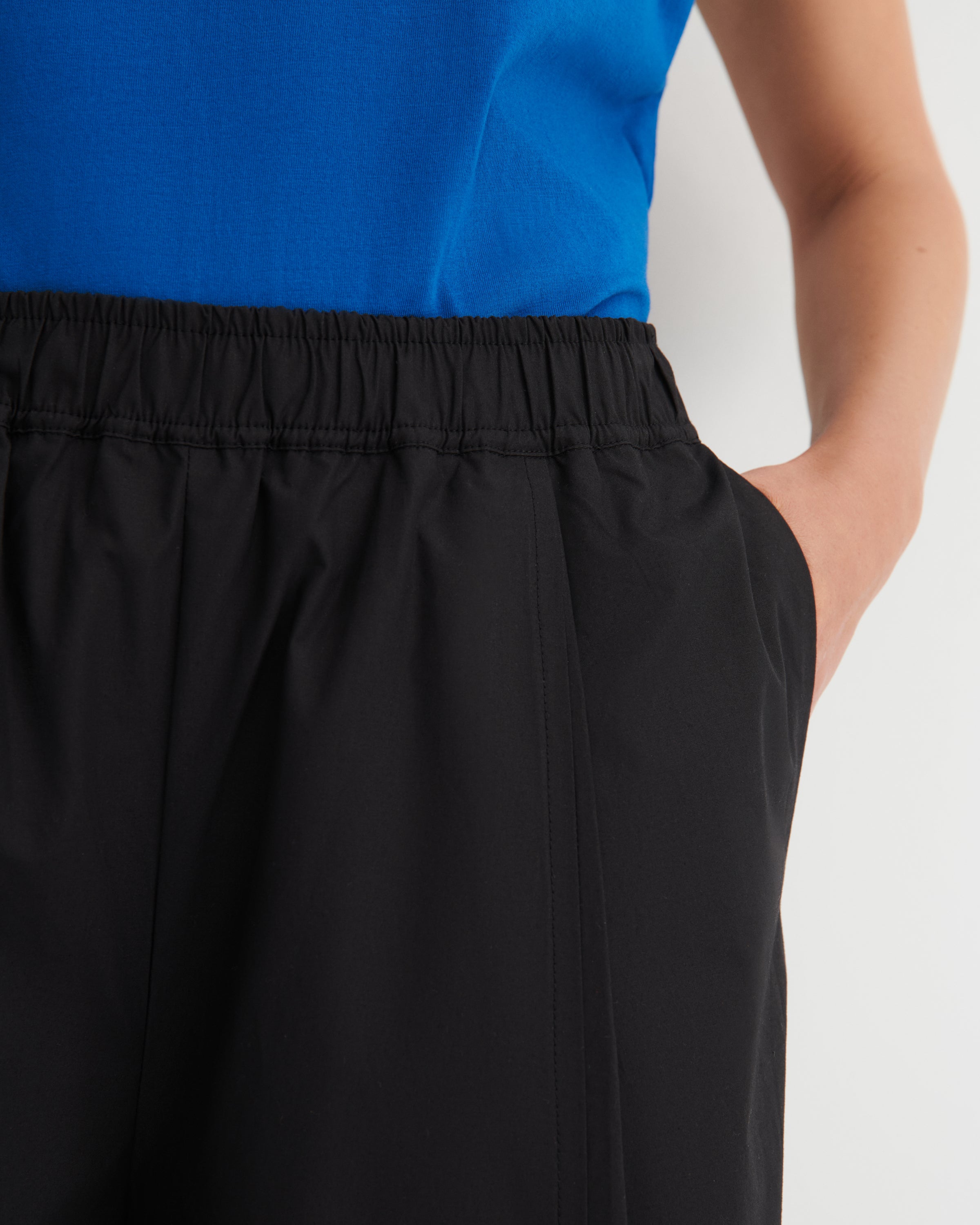 Person wearing a blue top and black pants on a white background