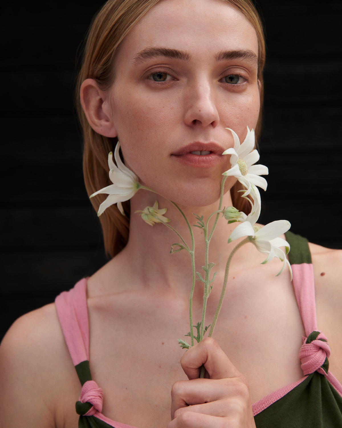 Woman holding white flowers against a black background