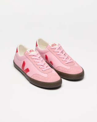 A pair of pink low-top sneakers with red side stripes and brown gum soles.