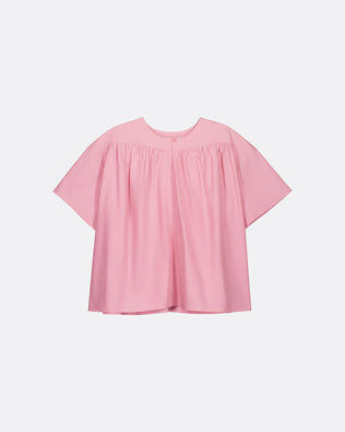 A light pink short-sleeve blouse with a gathered, smocked bodice and a relaxed, oversized silhouette, shown against a plain light gray background.