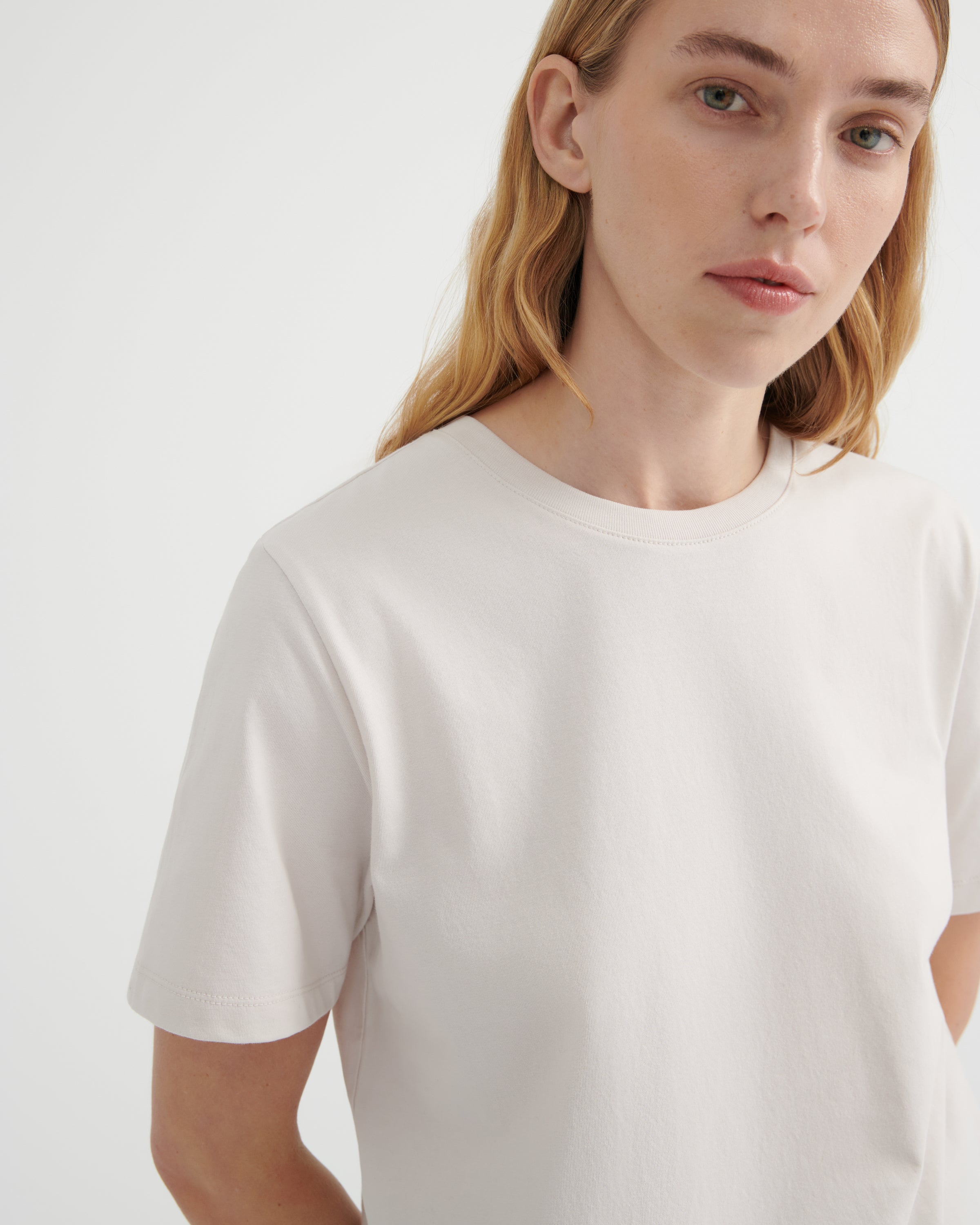 A close-up shot of a woman wearing a off-white crew-neck t-shirt.