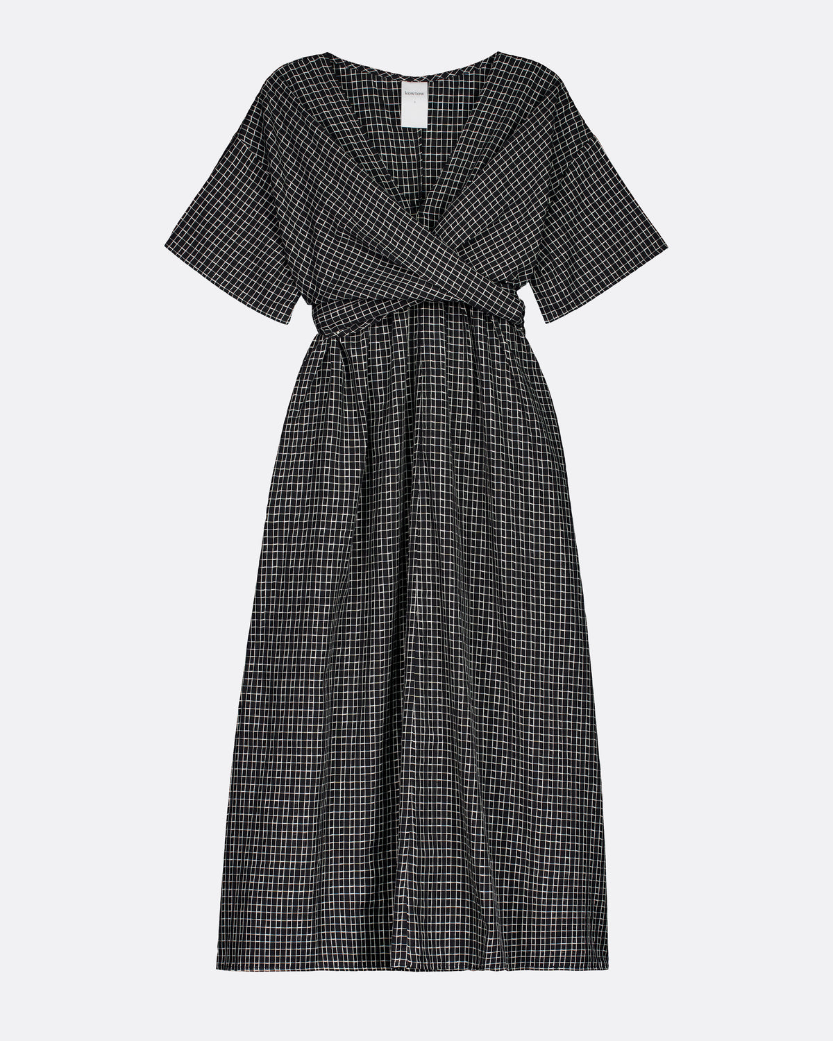 A short-sleeve midi dress with a black and white micro-check pattern, featuring a wrap-style V-neckline and a matching fabric tie belt at the waist, shown against a light gray background.