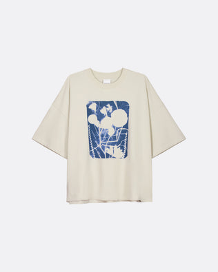 A cream-colored short-sleeve t-shirt with a blue and white abstract graphic print on the front, displayed against a light gray background.