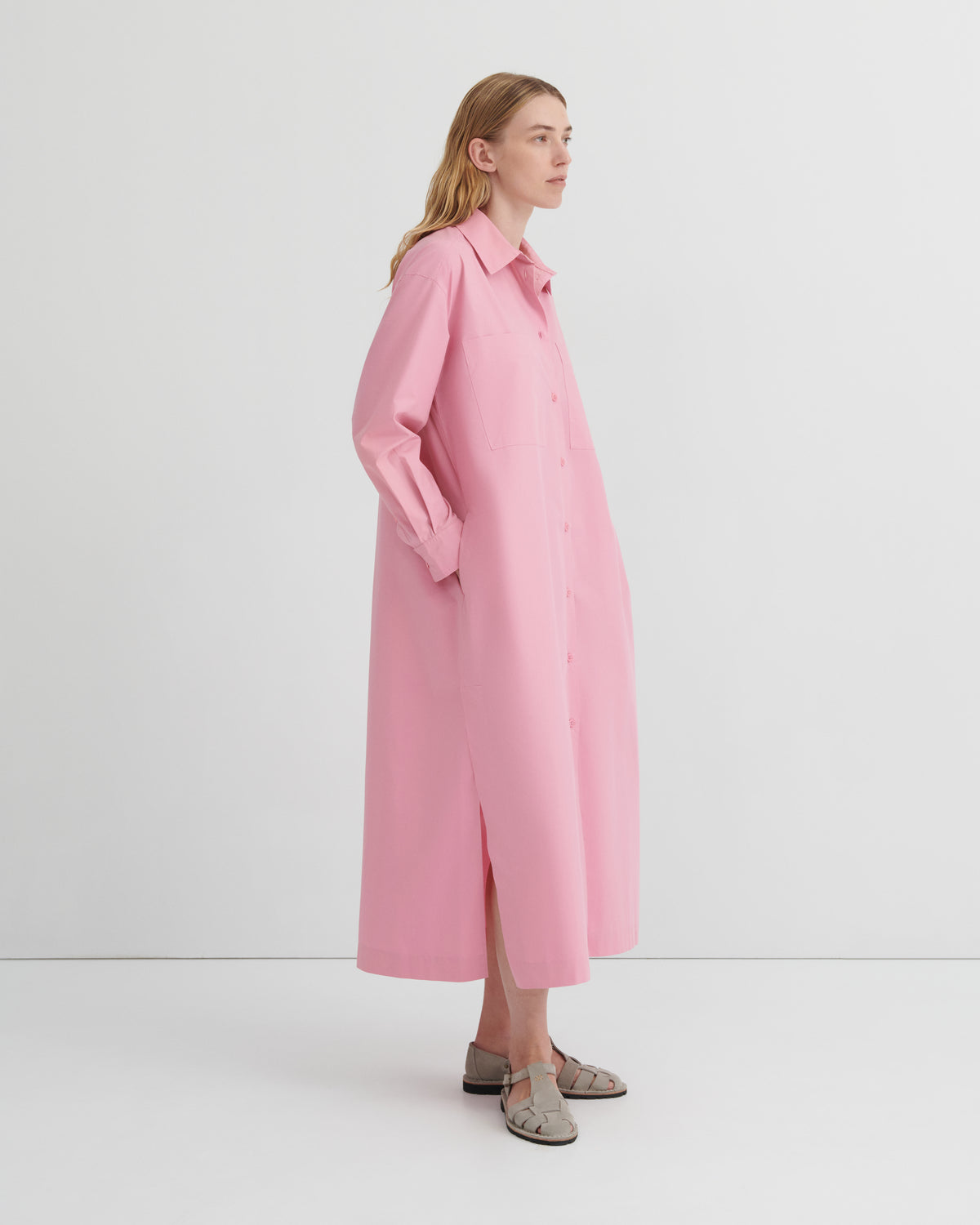 A women wearing a button up pink dress.