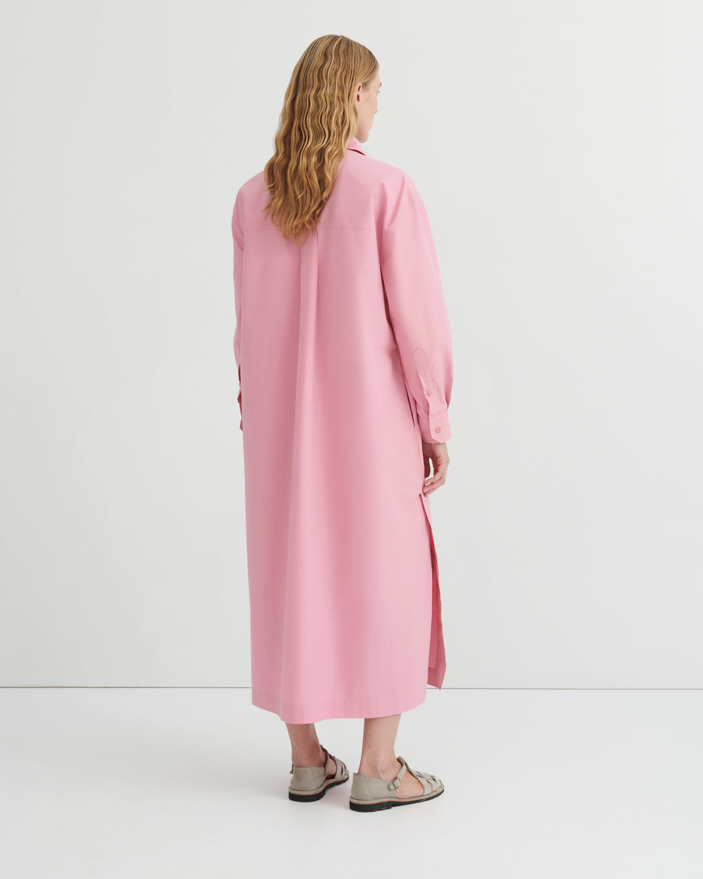 A women wearing a button up pink dress.