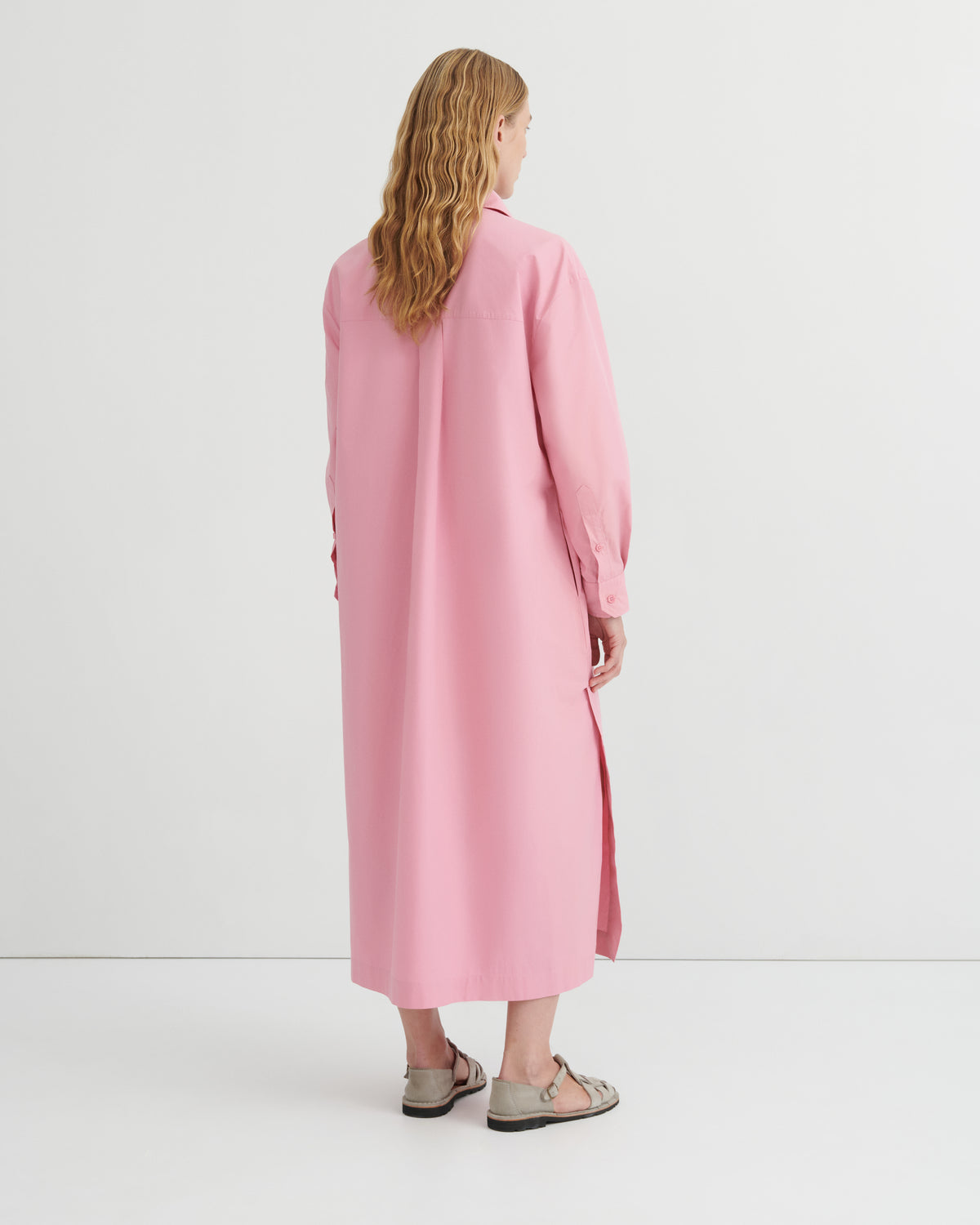 A women wearing a button up pink dress.