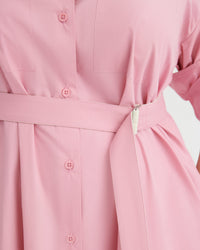 Close-up of a pink belted shirt dress with matching buttons, showing the waist tie and fabric texture.