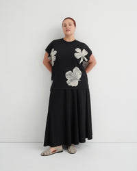 Person wearing a black dress with floral patterns on a white background