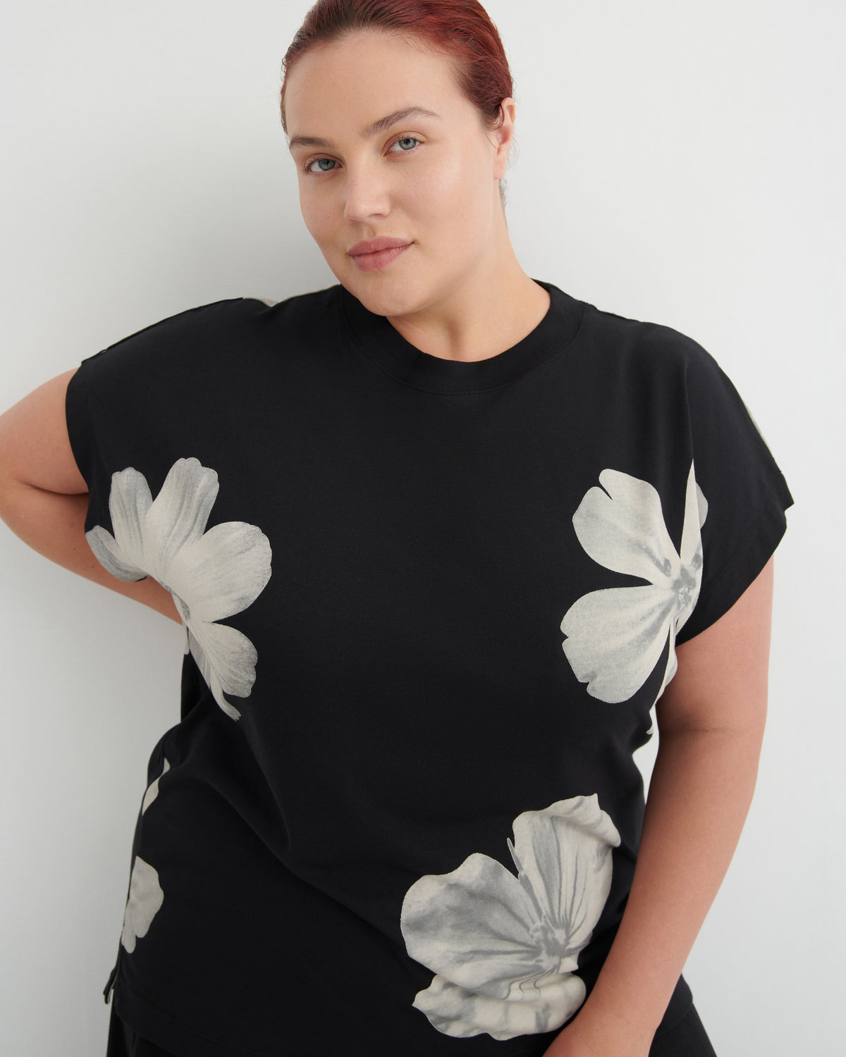 Woman wearing a black t-shirt with white floral patterns against a white background