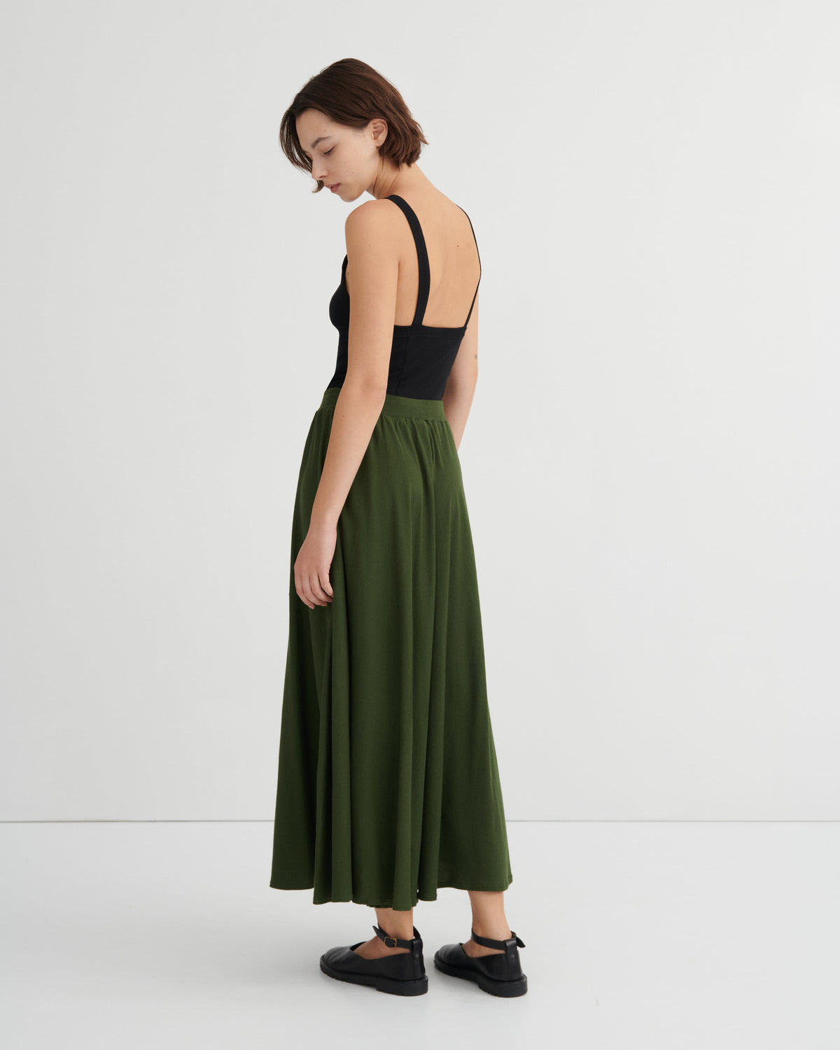 Woman wearing a black top and green skirt on a white background