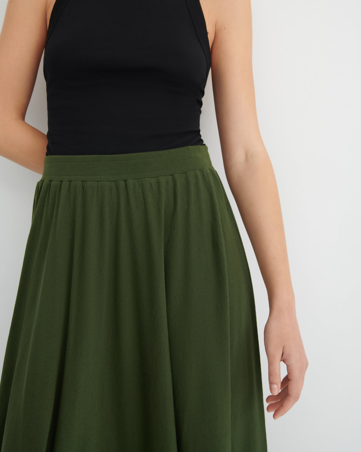 Person wearing a black top and green skirt on a white background