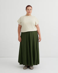 Person wearing a white top and green skirt on a white background