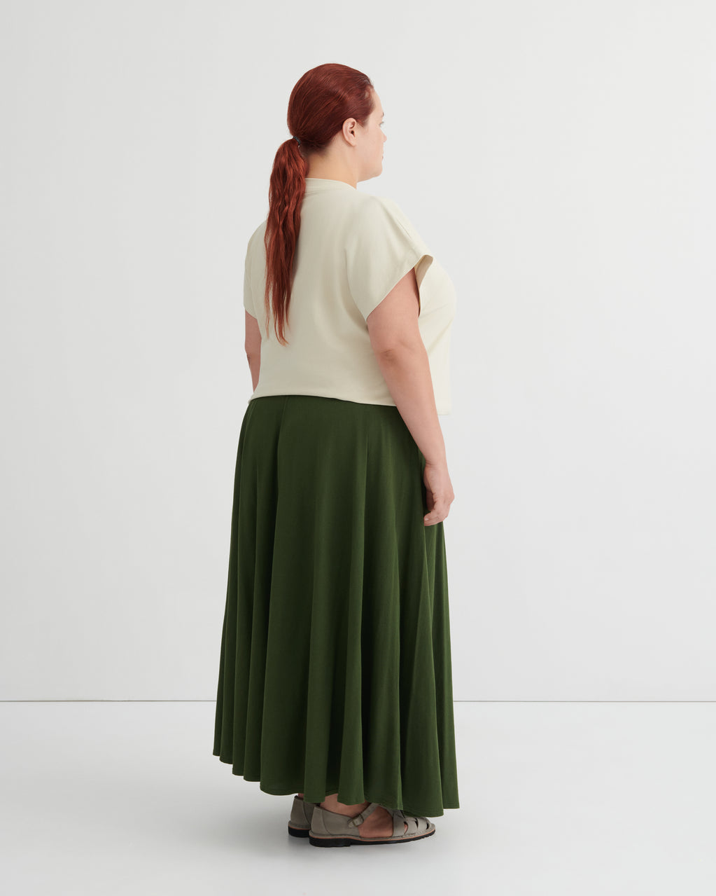 Person wearing a white top and green skirt on a white background