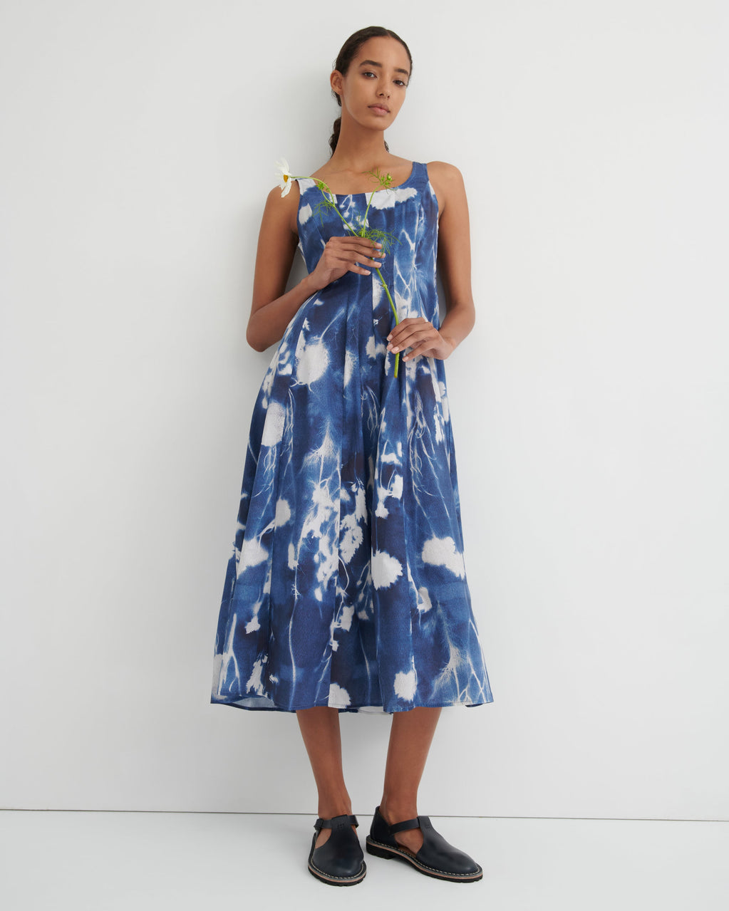Woman wearing a blue and white floral dress against a white background
