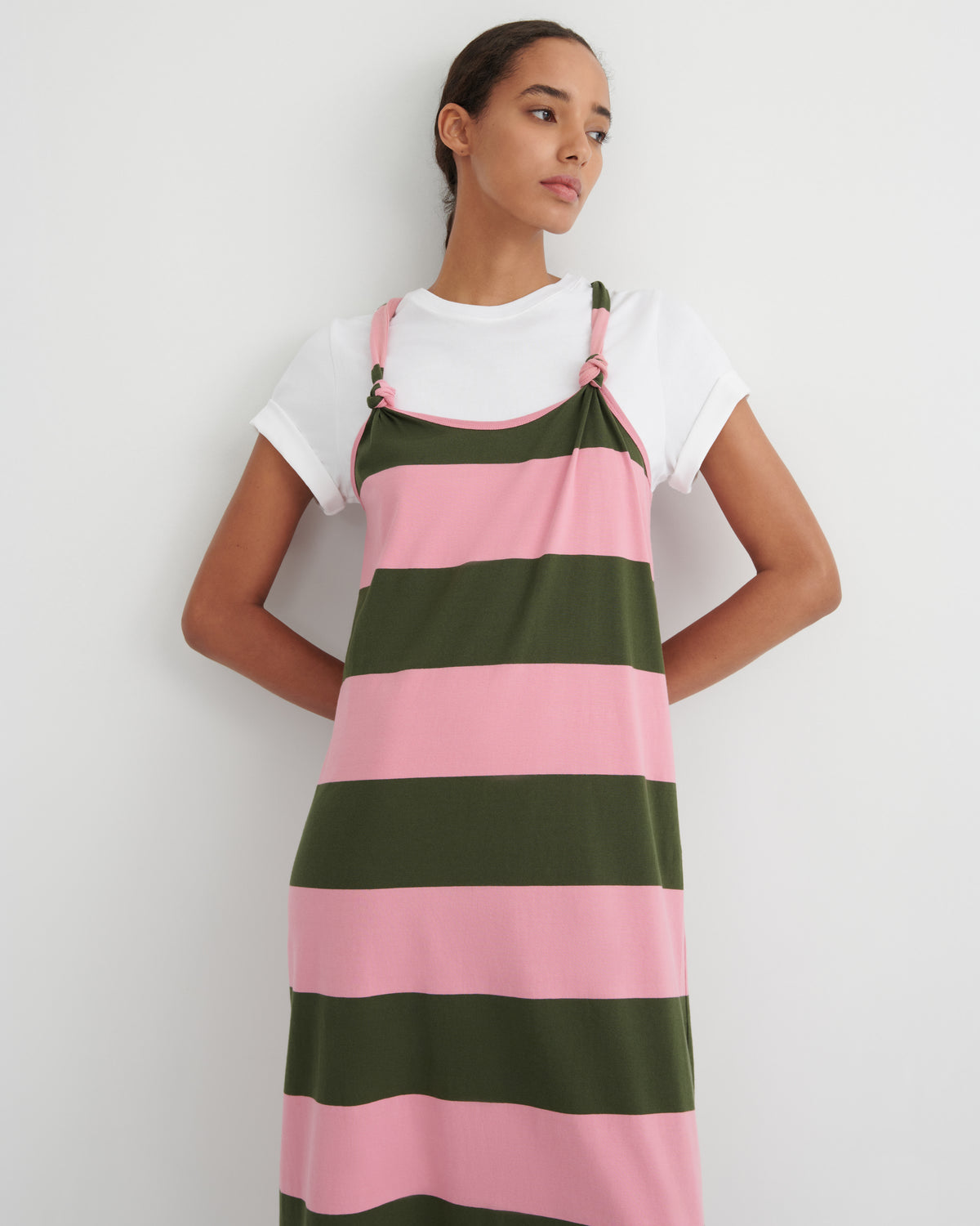 Woman wearing a pink and green striped dress over a white shirt on a plain background
