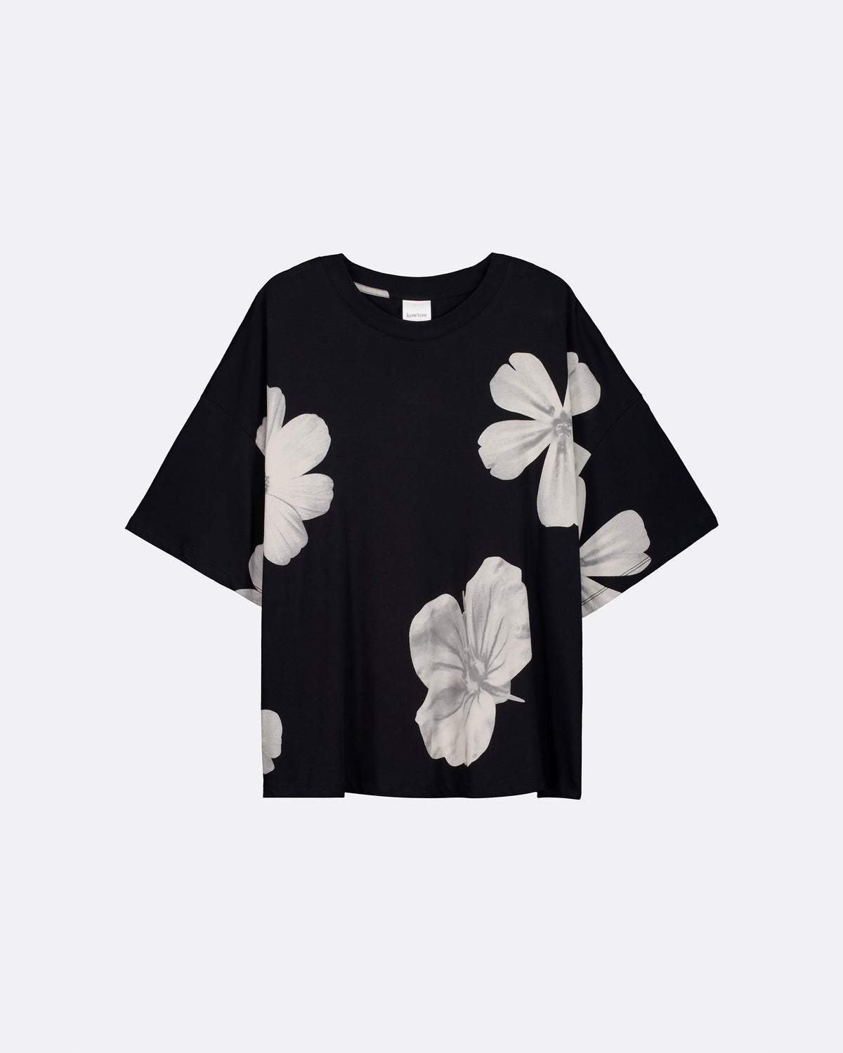 An oversized black tee with big white flowers sitting flat against a light grey background.
