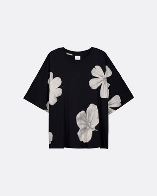 An oversized black tee with big white flowers sitting flat against a light grey background.