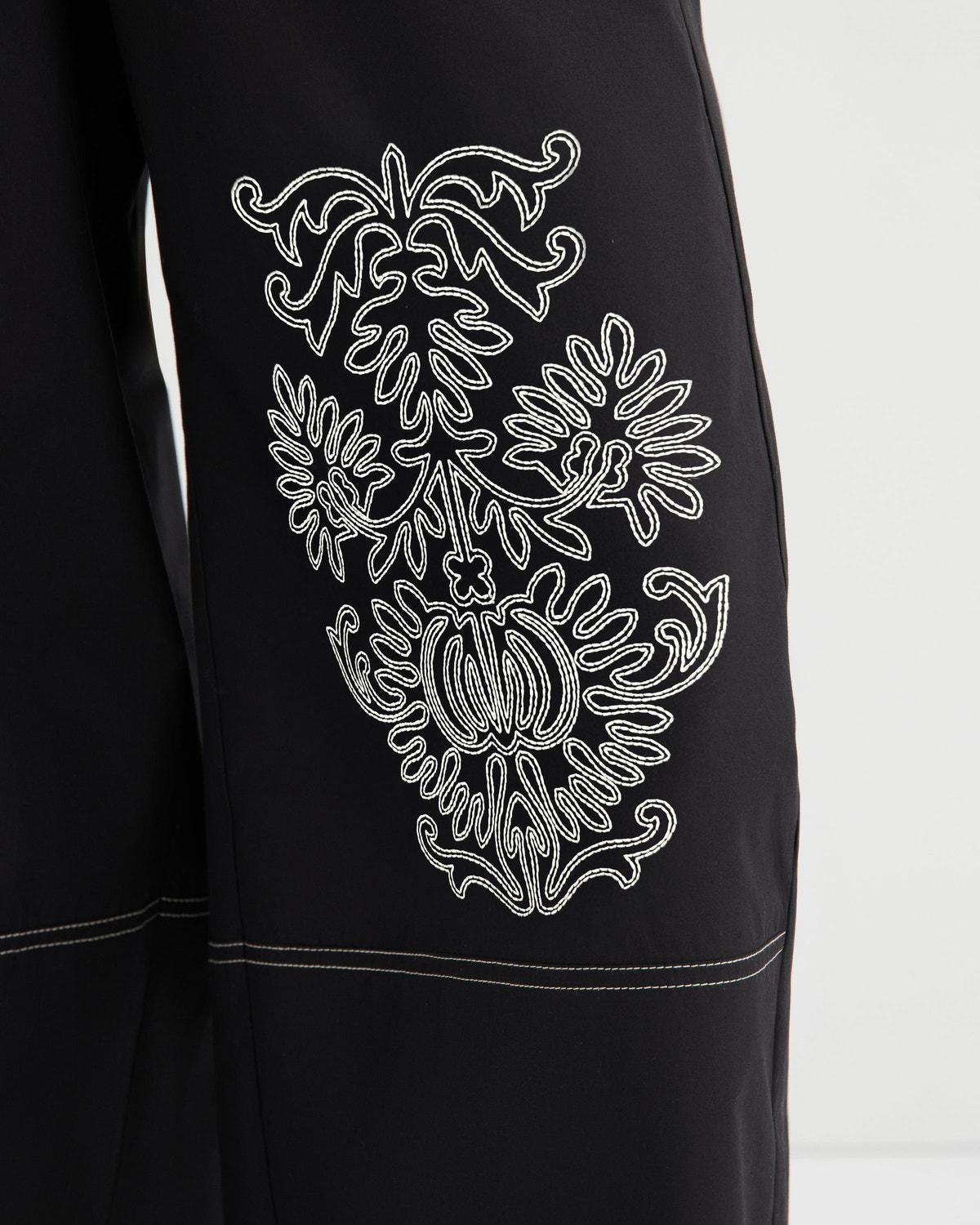 Black garment with white embroidered design on a white background