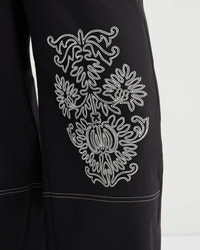 Black garment with white embroidered design on a white background
