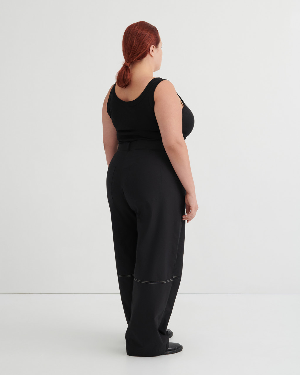 Person wearing a black singlet and pants against a white background