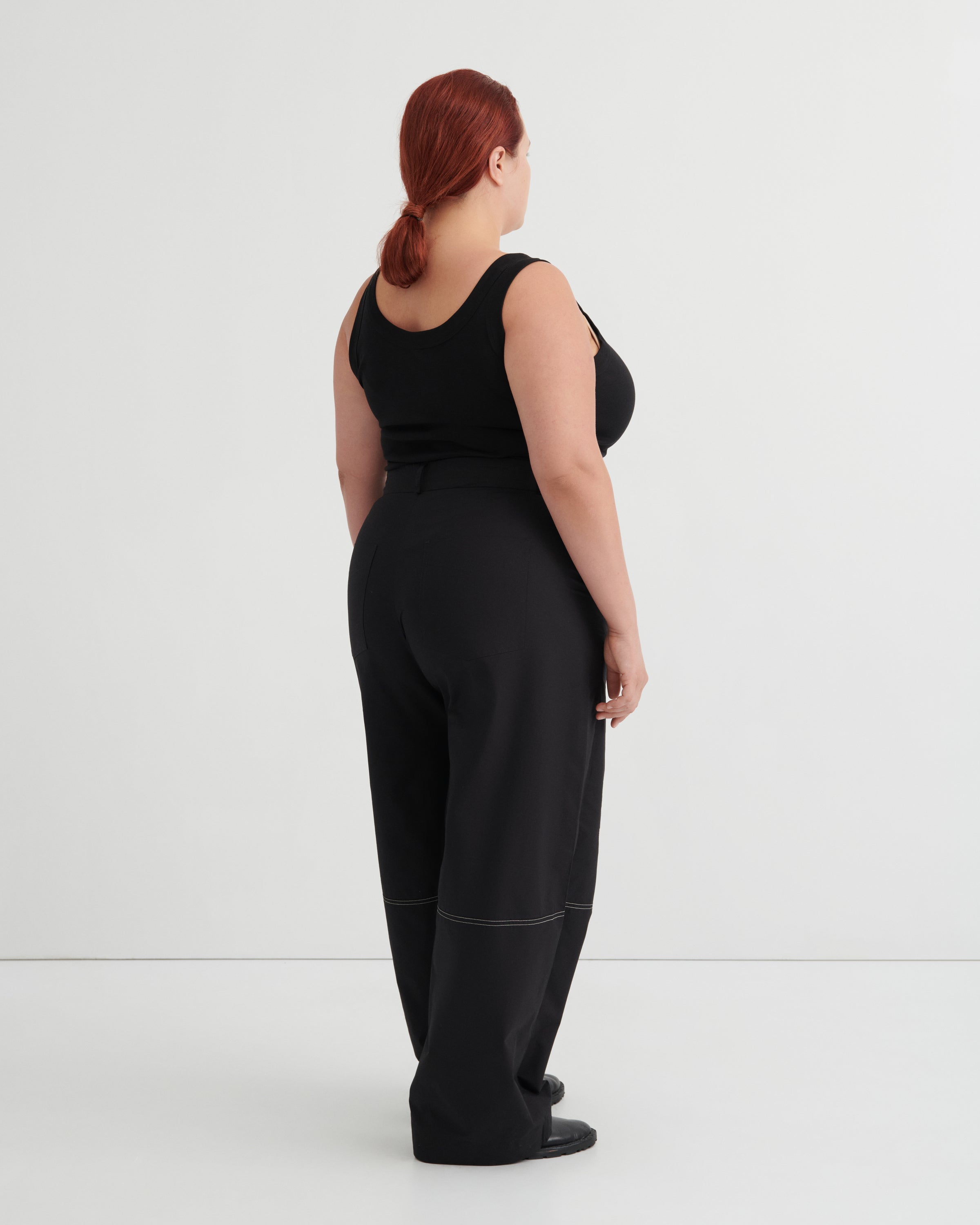 Person wearing a black singlet and pants against a white background