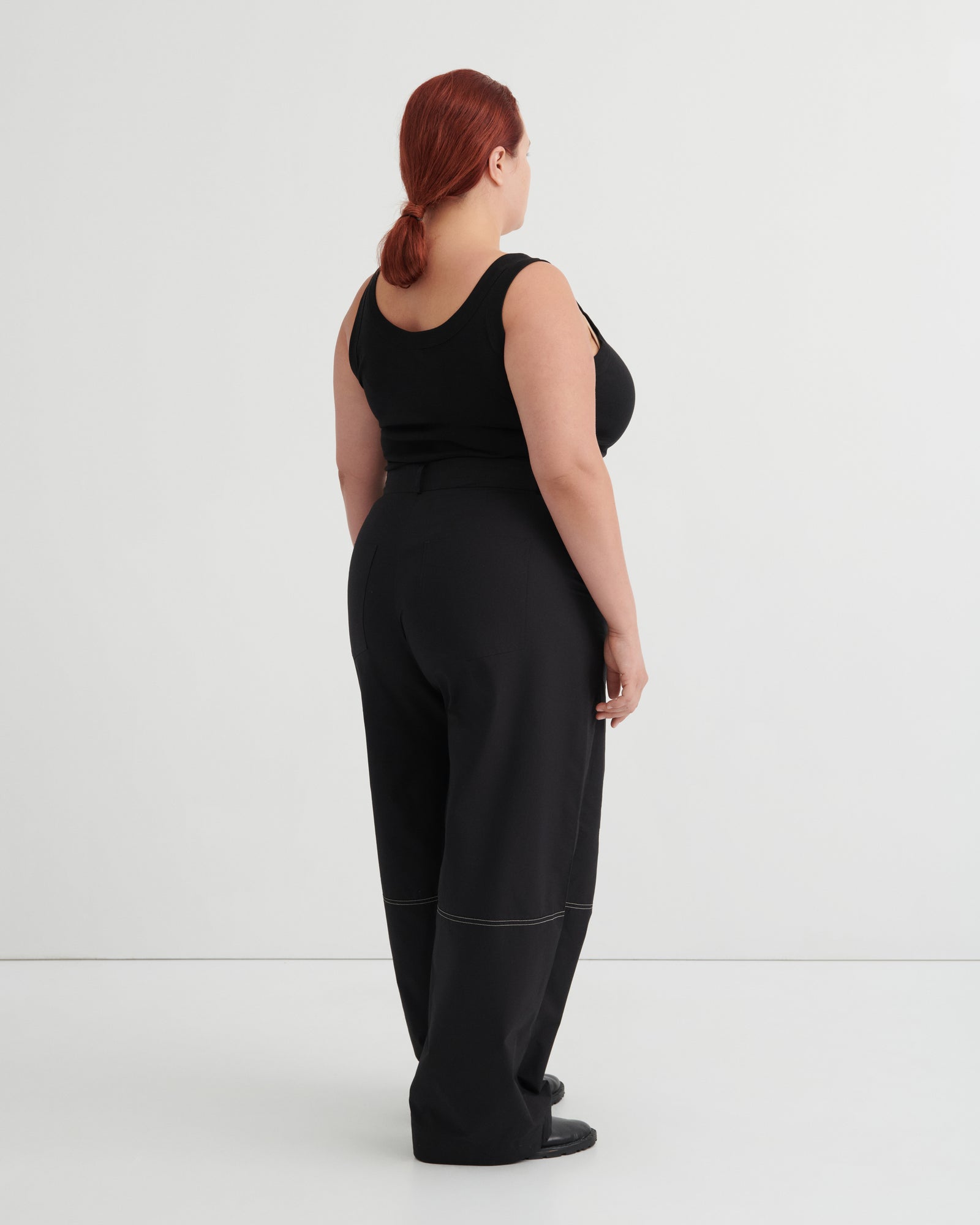 Person wearing a black singlet and pants against a white background