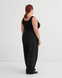 Person wearing a black singlet and pants against a white background