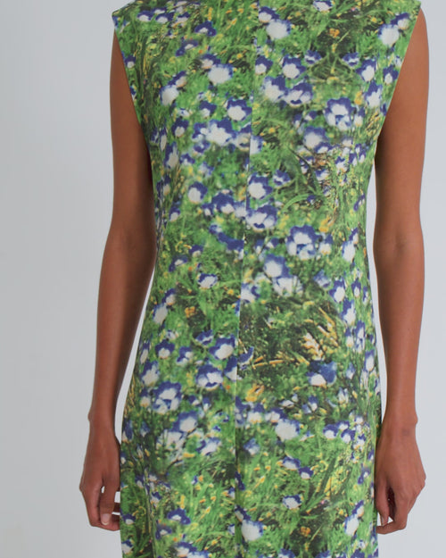 A women wearing a sleeveless midi floral dress against a grey background.
