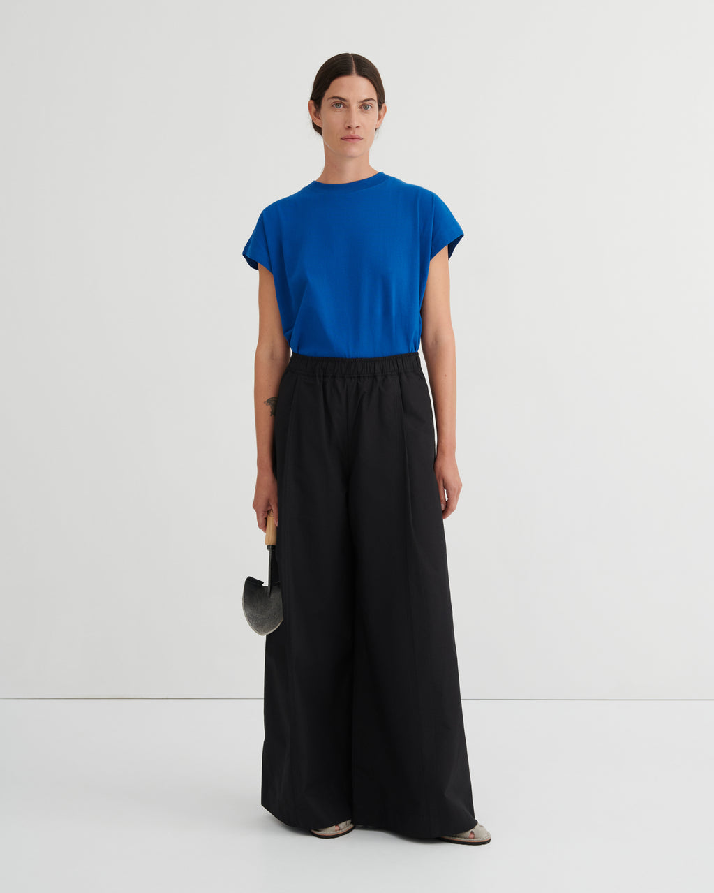 Woman wearing a blue top and black pants on a white background