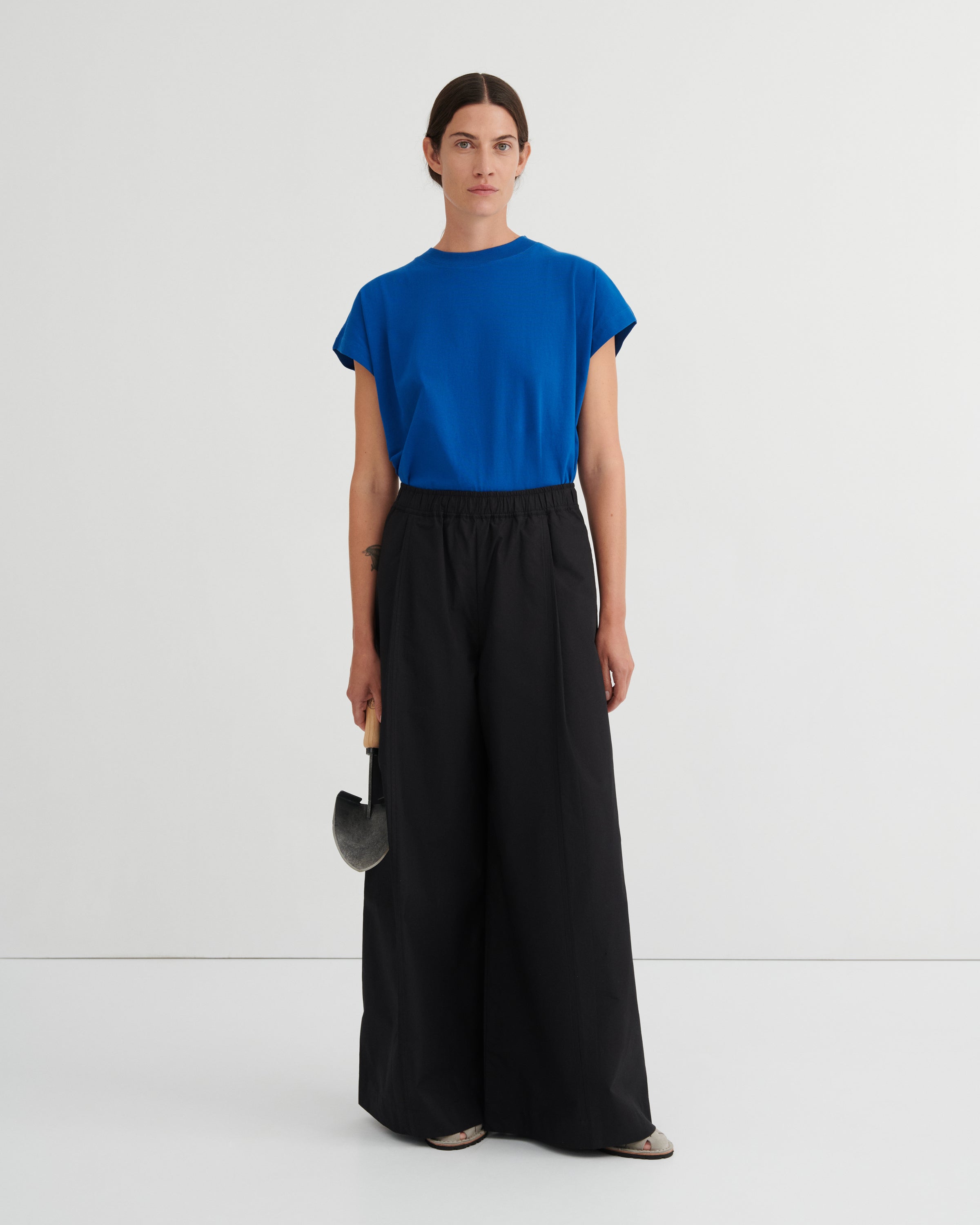 Woman wearing a blue top and black pants on a white background