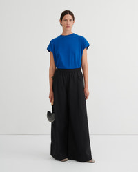 Woman wearing a blue top and black pants on a white background