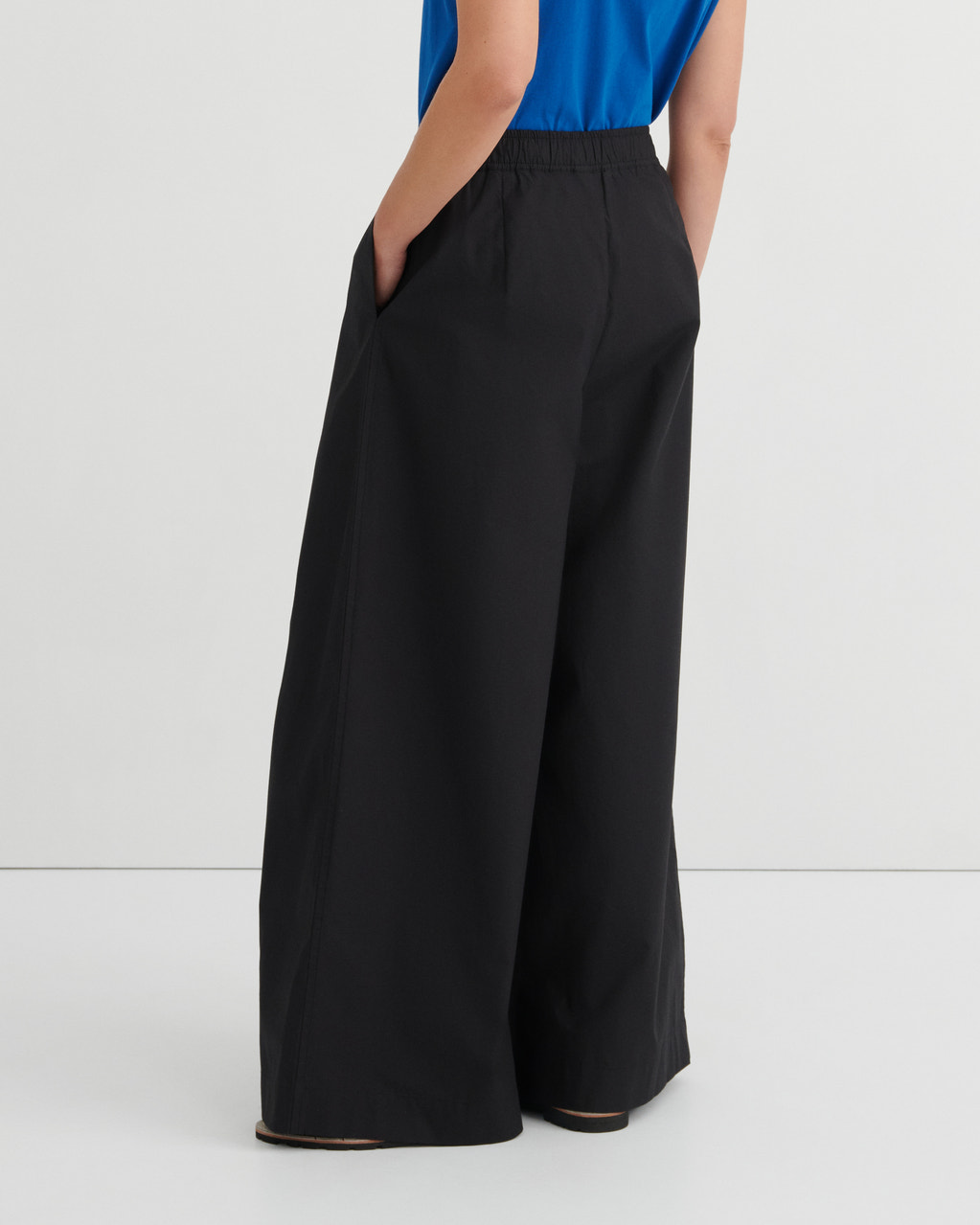 Black wide-leg pants worn by a person on a white background
