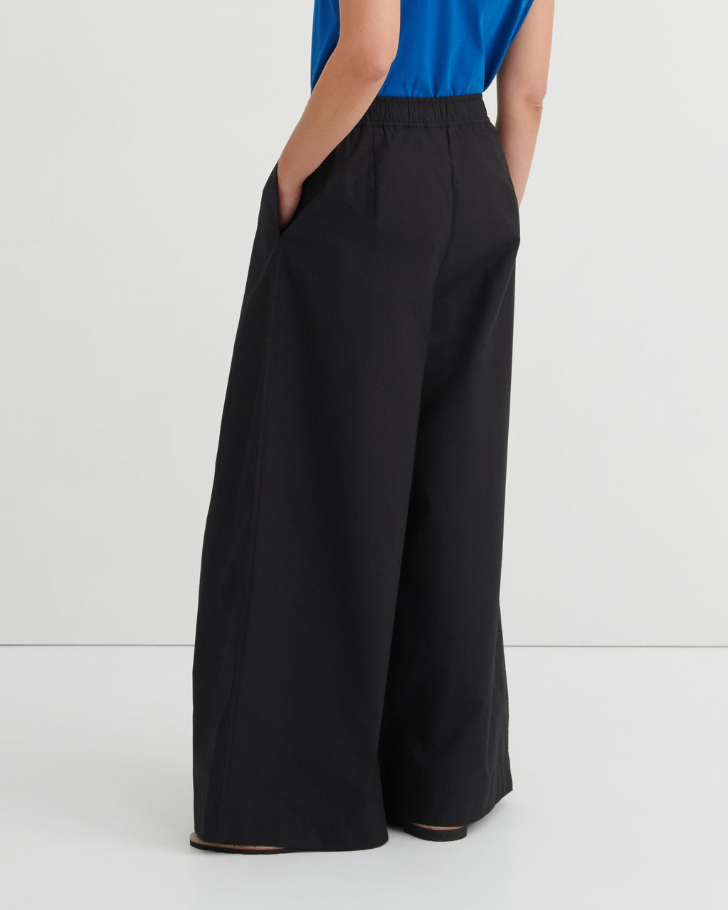 Black wide-leg pants worn by a person on a white background