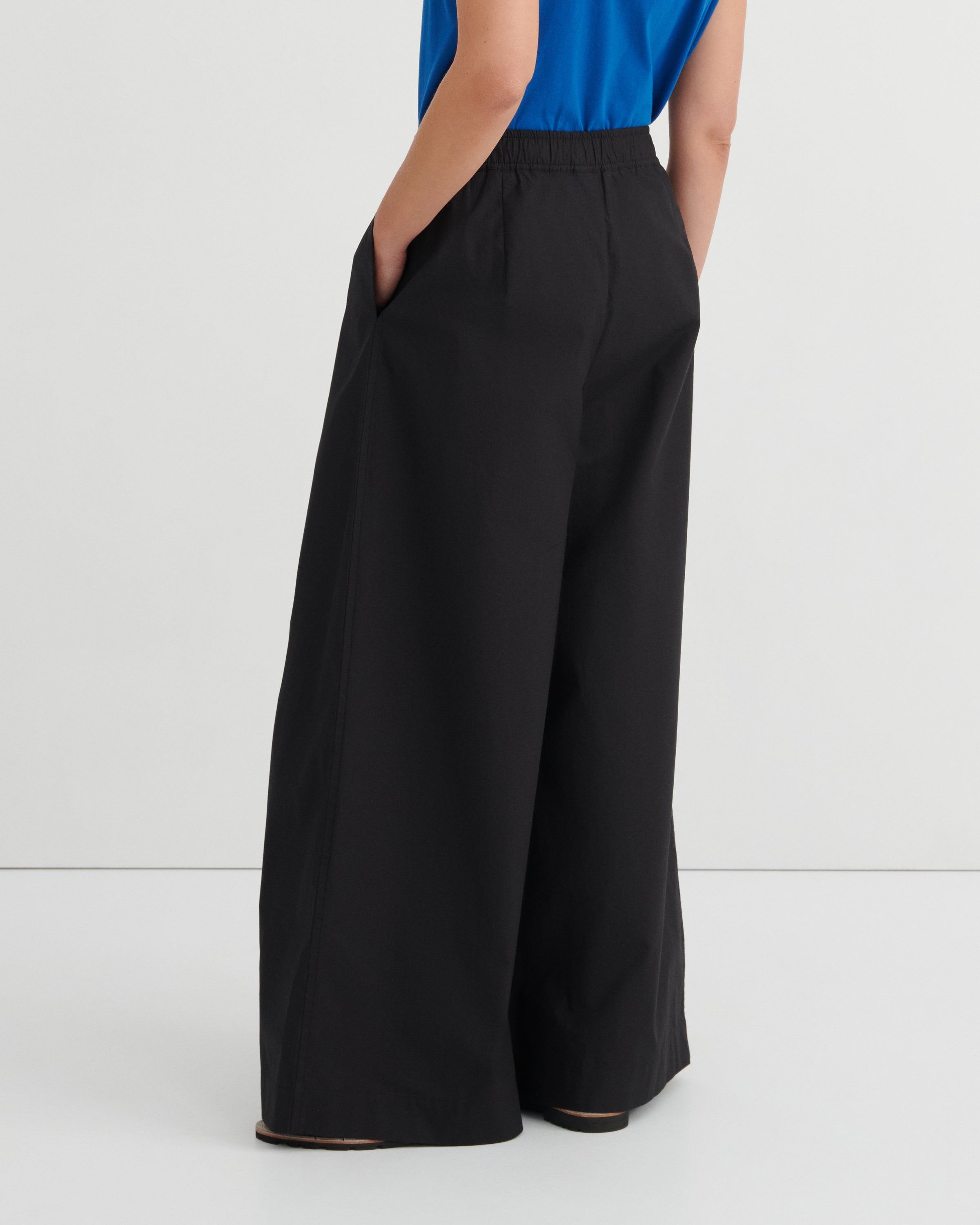 Black wide-leg pants worn by a person on a white background
