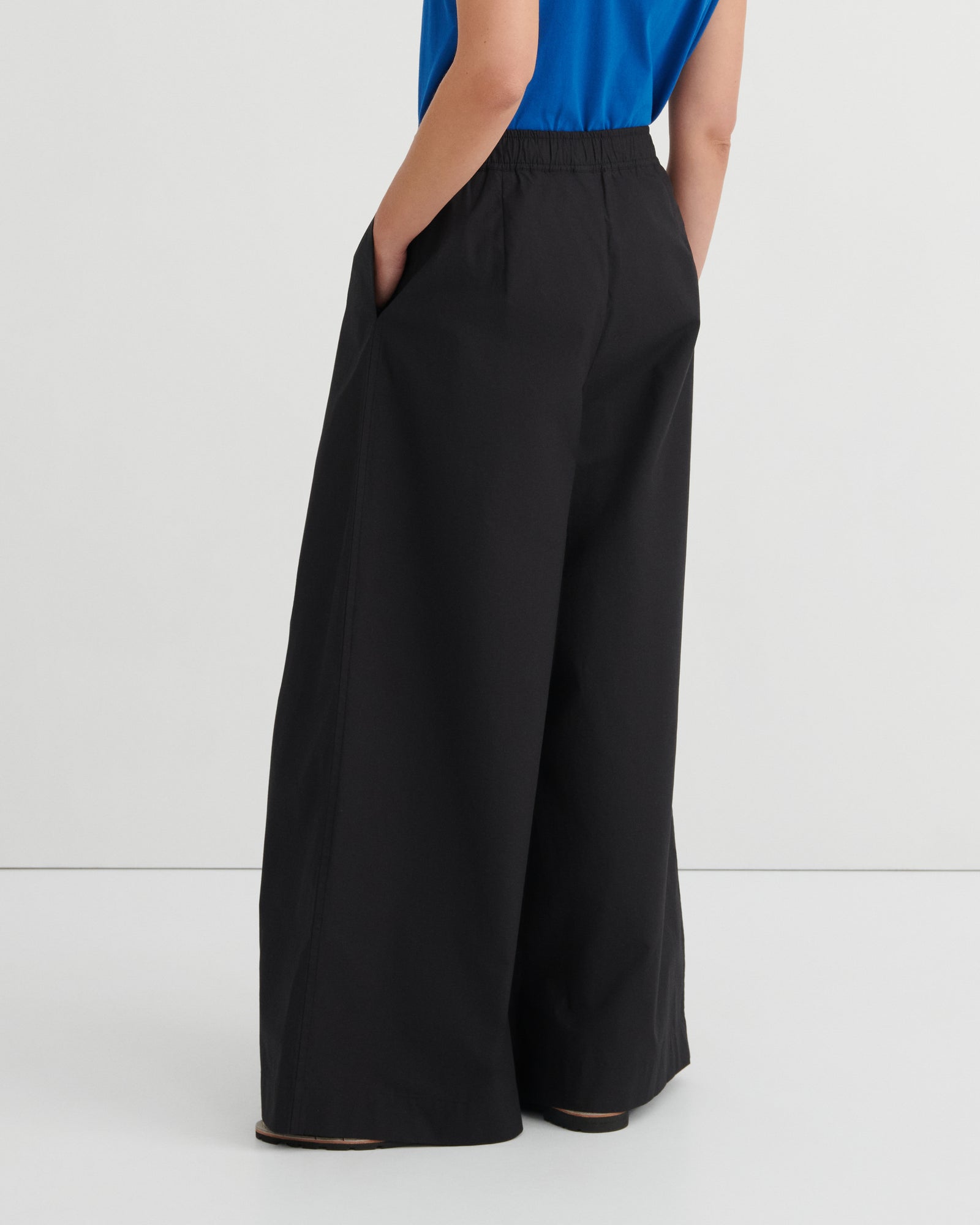 Black wide-leg pants worn by a person on a white background
