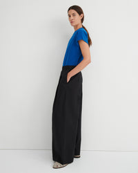 Woman wearing a blue top and black wide-leg pants against a white background